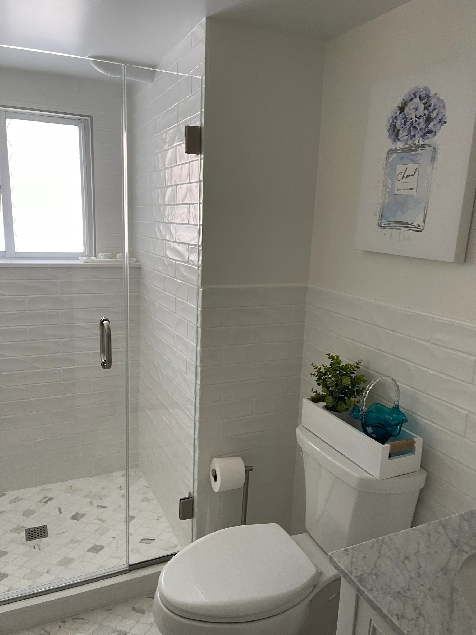 Finished white bathroom with glass shower, tiled walls, toilet, and vanity