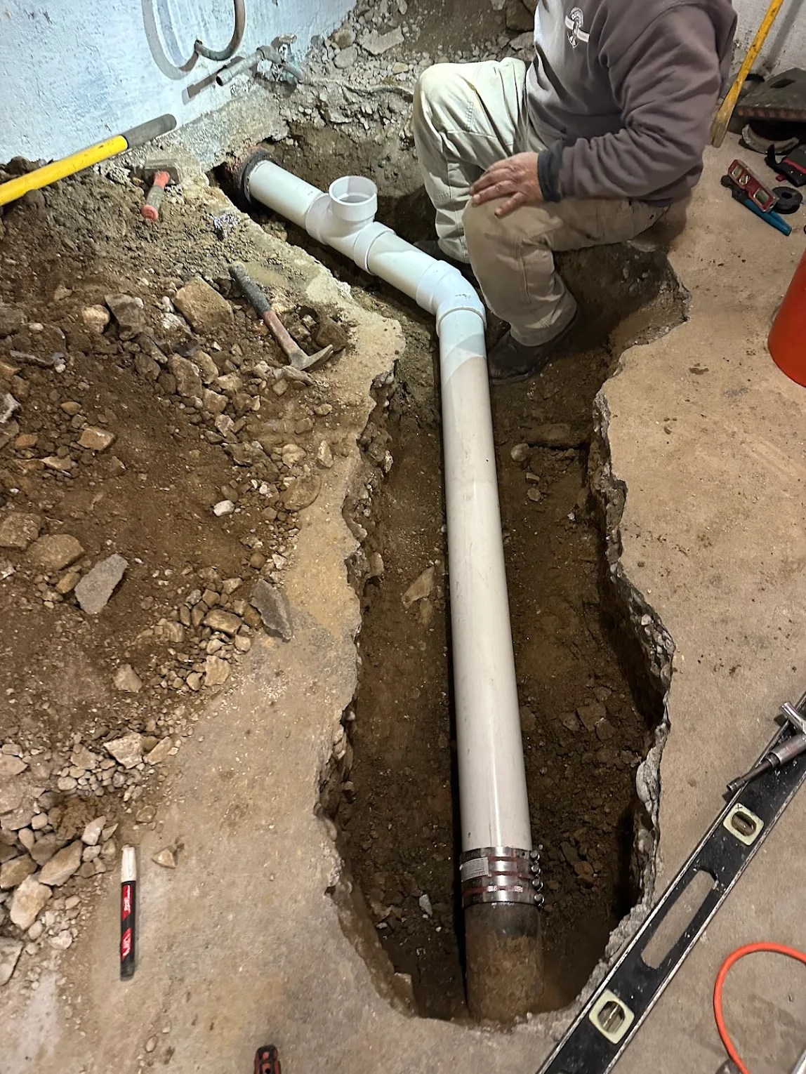 New white PVC drain pipe installed in an excavated basement trench