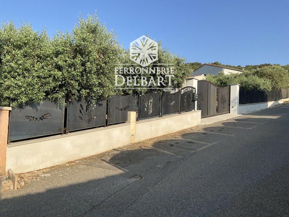 clôture portail en acier à motifs découpe laser fixé dans un muret entouré d'oliviers. Ferronnerie Delbart Les Mées en Haute-Provence