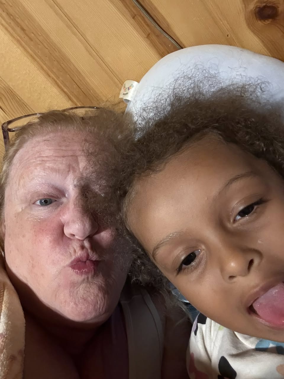 Photo of Delight with a small human child looking into the lens of a camera-capable cellular phone.
