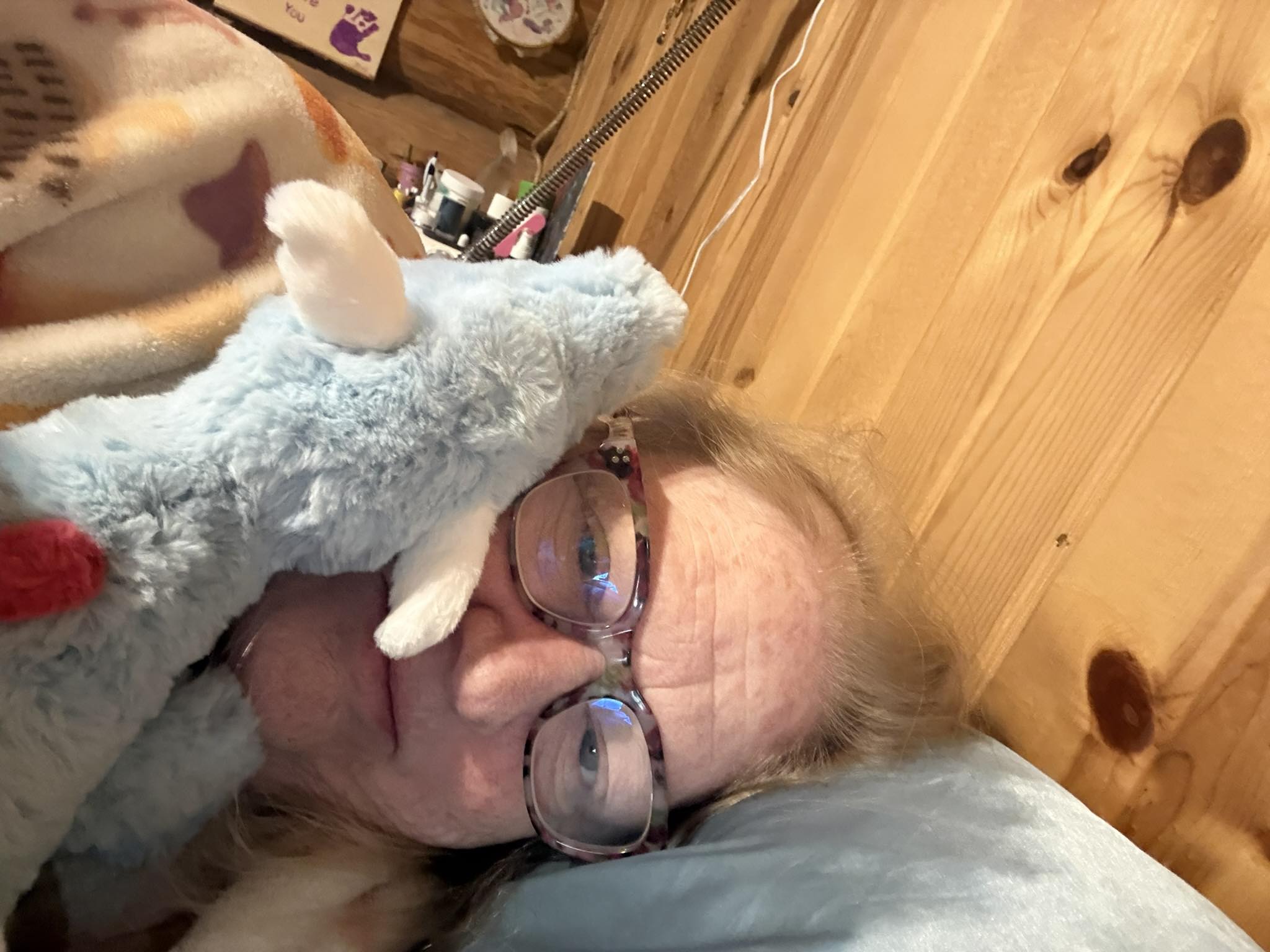 Delight holding a stuffed toy dragon while laying down.