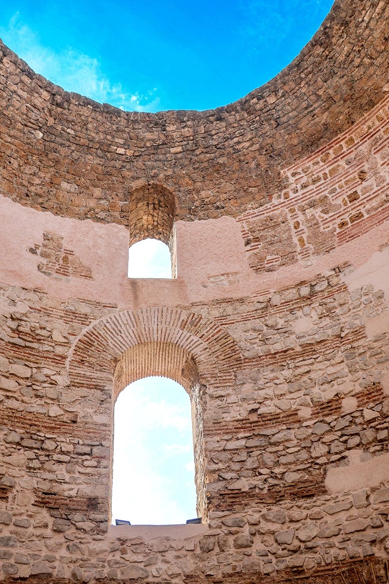 Vista da abertura circular do Vestíbulo em Split, Croácia, com o céu azul visível através dos arcos.