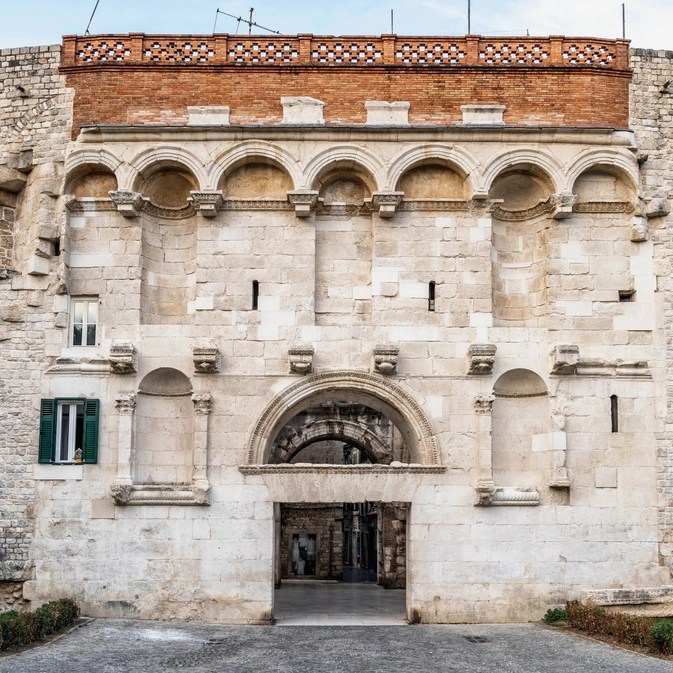 Histórica Porta de Ouroem Split, Croácia, com arcos e entalhes intricados, apresentando uma passagem que leva a um pátio interno.
