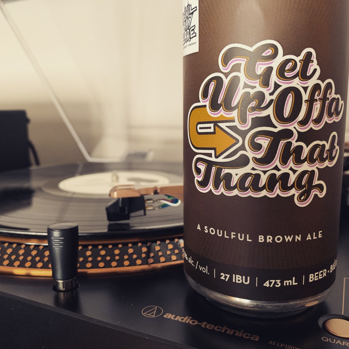 A can of Get Up Offa That Thang beside a turntable