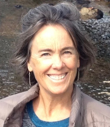 Photo of Diana Badger, white woman with brown hair in front of a small body of water