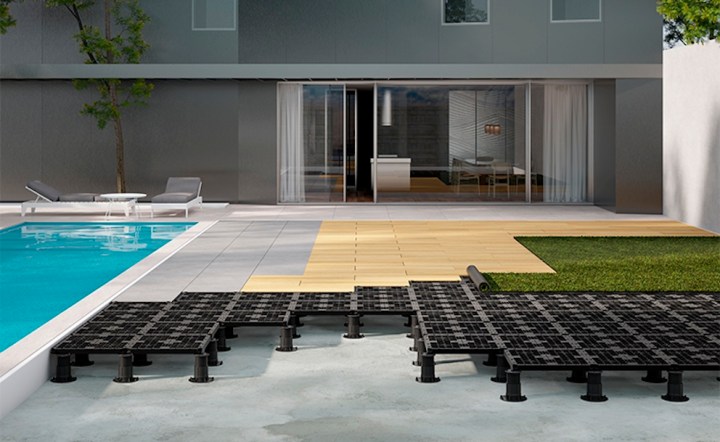 Modern backyard with a swimming pool, sleek loungers, and a composite decking area featuring black tiles and grass.
