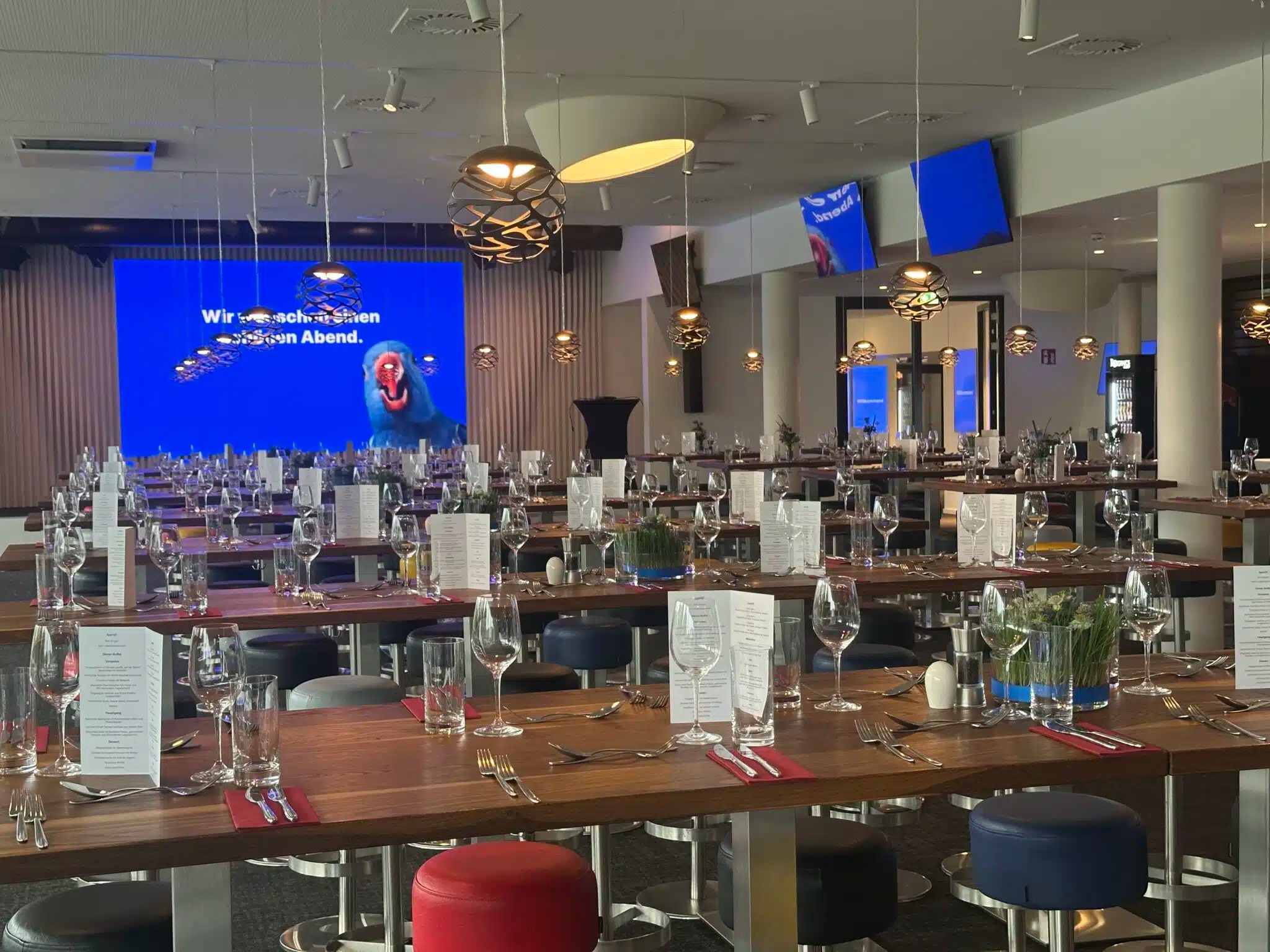 Gedeckte Banketttafeln im Business-Club der Red Bull Arena mit blauer Leinwand