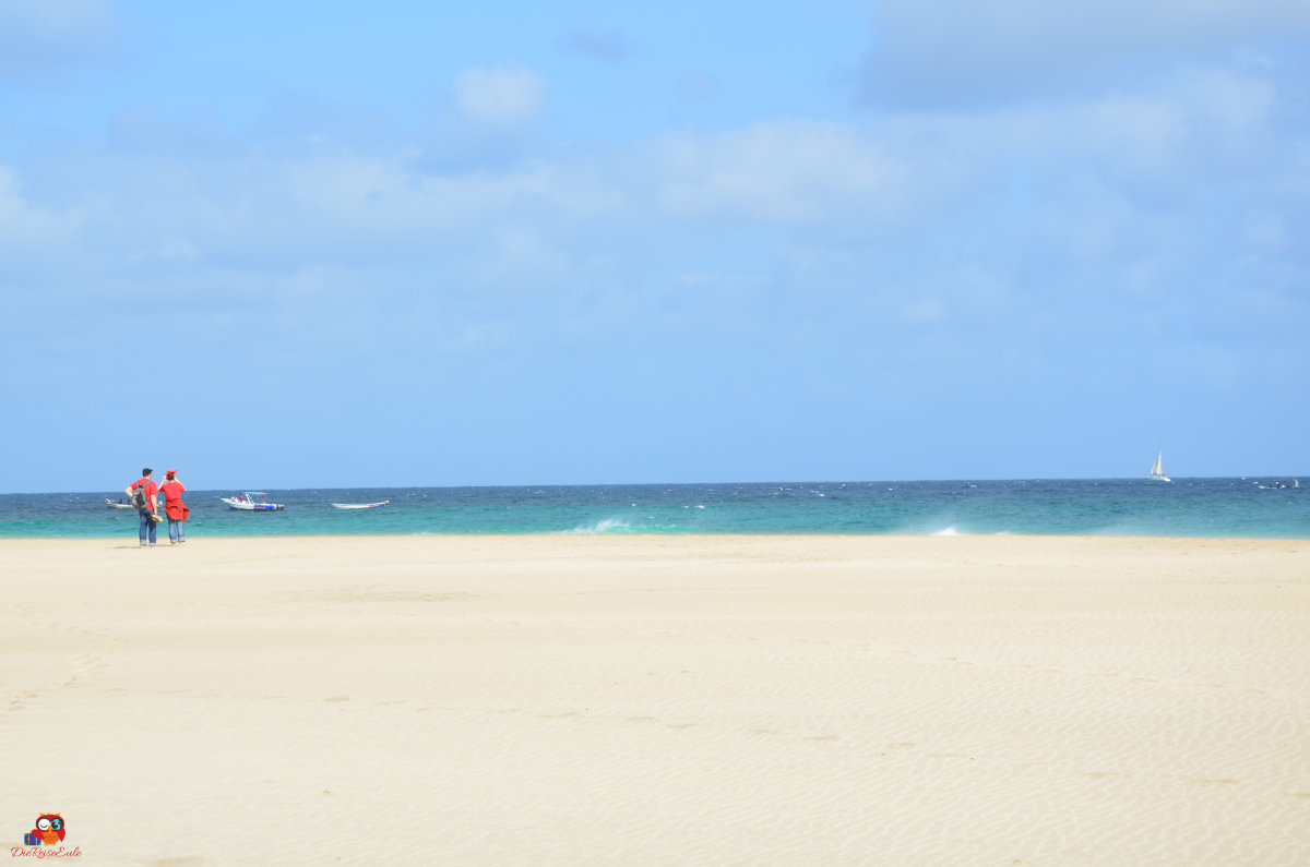 weißer sandstrand, links zwei personen, die auf das meer schauen