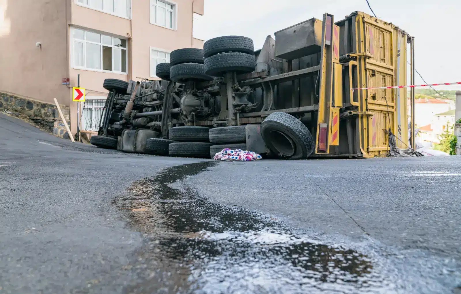 A tipped over truck leaking fuel all over the asphalt