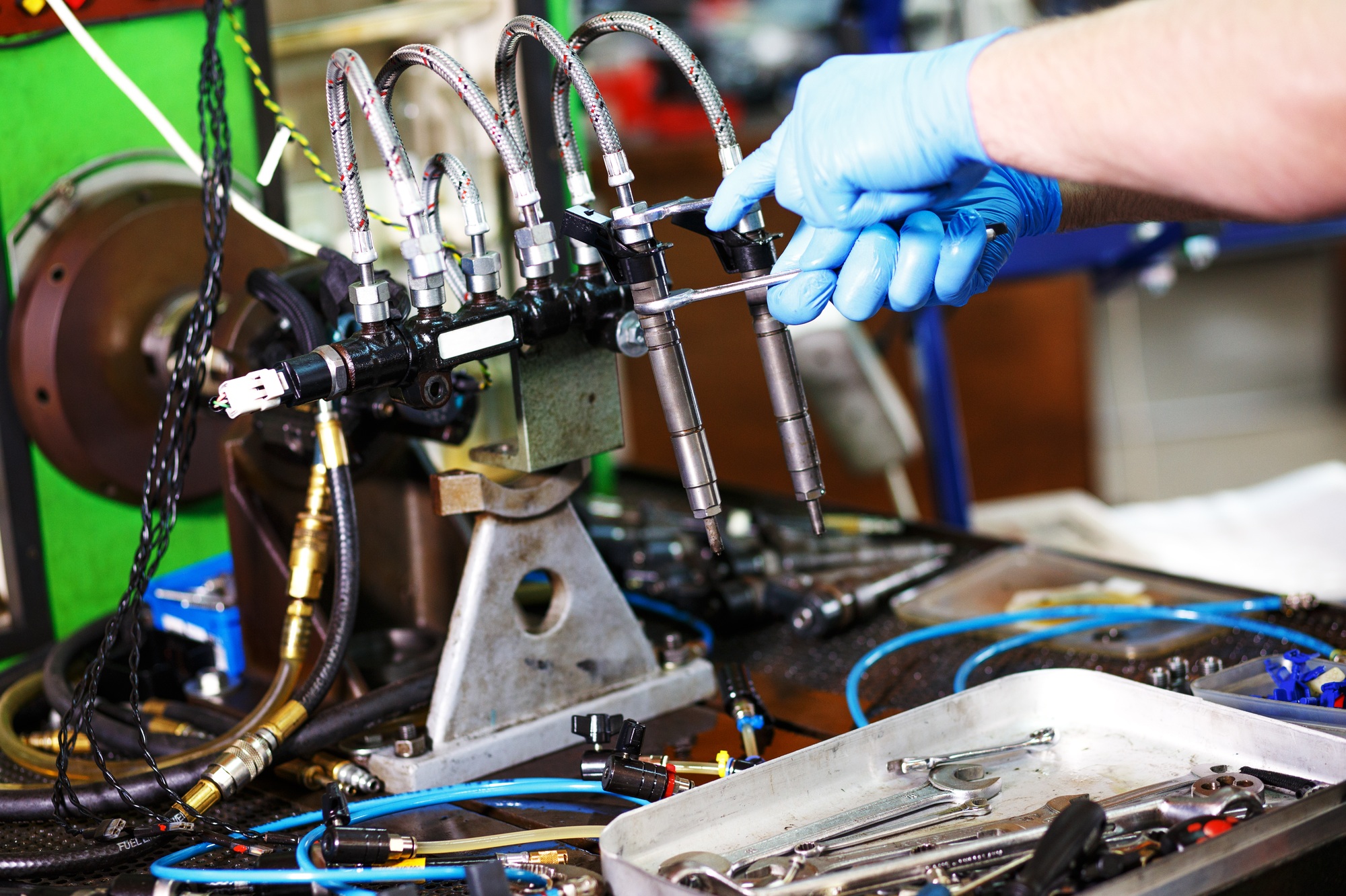 Professional mechanic testing diesel injector in his workshop.
