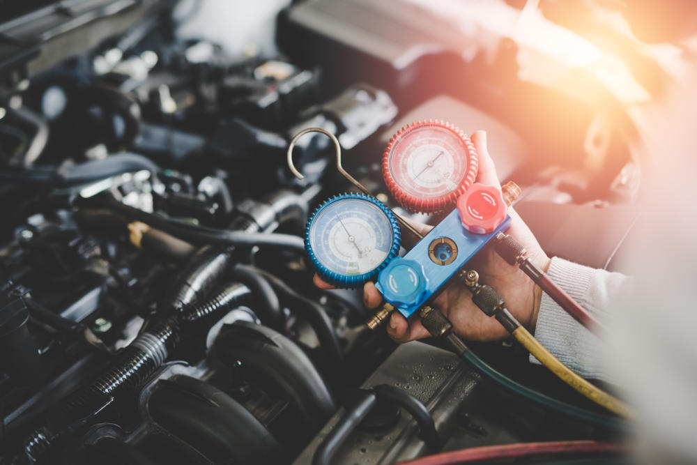 Hand of young mechanic with Gauges Set, Check the pressure and leak. Servicing car air conditioner