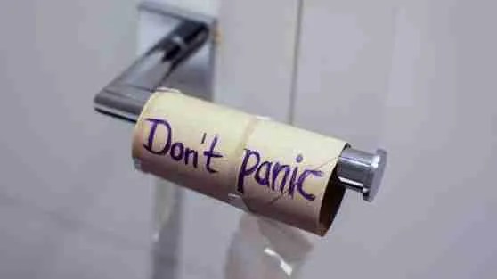 An empty toilet paper roll sits on a holder, featuring the handwritten message Dont panic, offering a touch of humor in stress management.