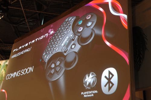 A promotional image displaying a PlayStation 3 wireless game controller against a backdrop featuring dynamic red and white curves. Text on the image announces 'COMING SOON' and highlights the PlayStation Network and Bluetooth compatibility.