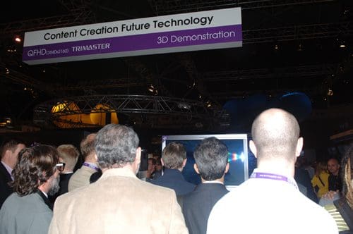 A group of spectators gathered around a display at an exhibition, with a sign above reading "Content Creation Future Technology" and "3D Demonstration." The crowd shows engagement with the presentation.