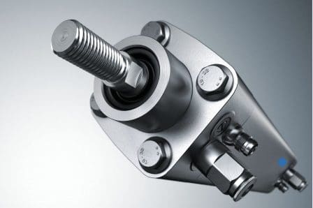 A close-up view of a metallic hydraulic component featuring a threaded rod and several bolts. The sleek design includes a circular base with a black seal and fluid connections, set against a gradient background.
