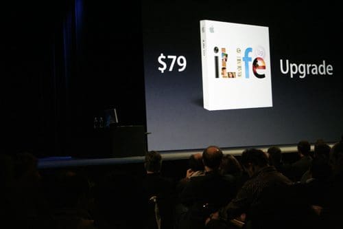 A presentation screen displaying an iLife upgrade box, with the price tag of $79 and the word 'Upgrade' prominently featured. An audience is visible in the foreground, engaged with the presentation.