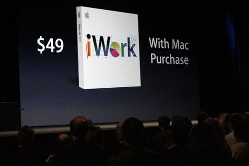 An image of a large screen displaying a promotional offer for iWork 09, showing the product box with text indicating the price of $49 alongside the phrase 'With Mac Purchase.' An audience is visible in the foreground.