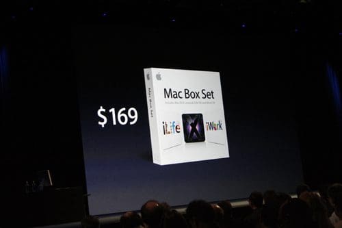 A presentation slide displaying an Apple Mac Box Set for $169, featuring icons for 'iLife' and 'iWork' on a large screen, with an audience visible in shadowed profile in the foreground.