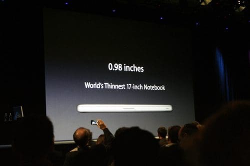 A presentation slide displaying the text "0.98 inches" and "World's Thinnest 17-inch Notebook," with an image of a sleek laptop at the bottom. An audience is seated in the foreground, partially obscured.