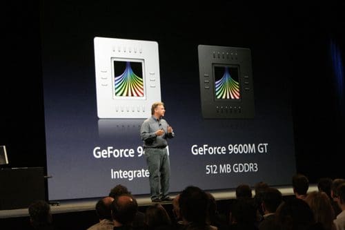 A presenter stands on stage during a tech conference, gesturing towards a large screen. The screen displays two graphics cards: GeForce 9400M on the left and GeForce 9600M GT on the right, highlighting their specifications.