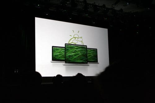 A presentation screen displaying three laptops with vibrant green graphics, set against a white background. The scene suggests a technology event with a focus on innovative design.