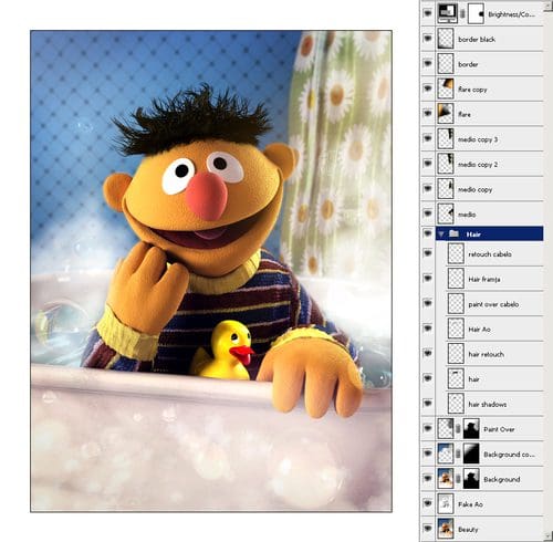 A cheerful yellow puppet character with orange nose and dark hair, sitting in a bathtub with a yellow rubber duck. The background features blue polka dots and flowers, creating a playful atmosphere.
