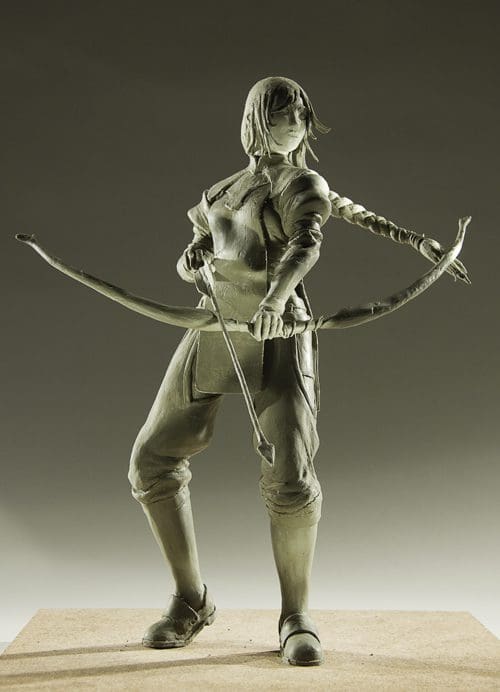 A detailed clay sculpture of a female archer standing in a dynamic pose. She holds a bow in one hand, with a quiver slung over her shoulder. Her braided hair and confident expression convey determination.