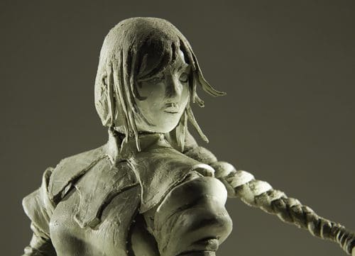 A detailed sculpture of a female figure with short hair and an expressive face, wearing a fitted outfit. The figure is positioned to the side, with a long braid cascading down her back, set against a neutral background.