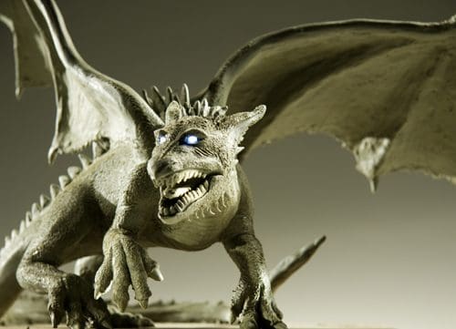 A detailed sculpture of a dragon with large wings, sharp claws, and glowing blue eyes, poised on a base. The dragon's textured skin and fierce expression convey a sense of power and intimidation.