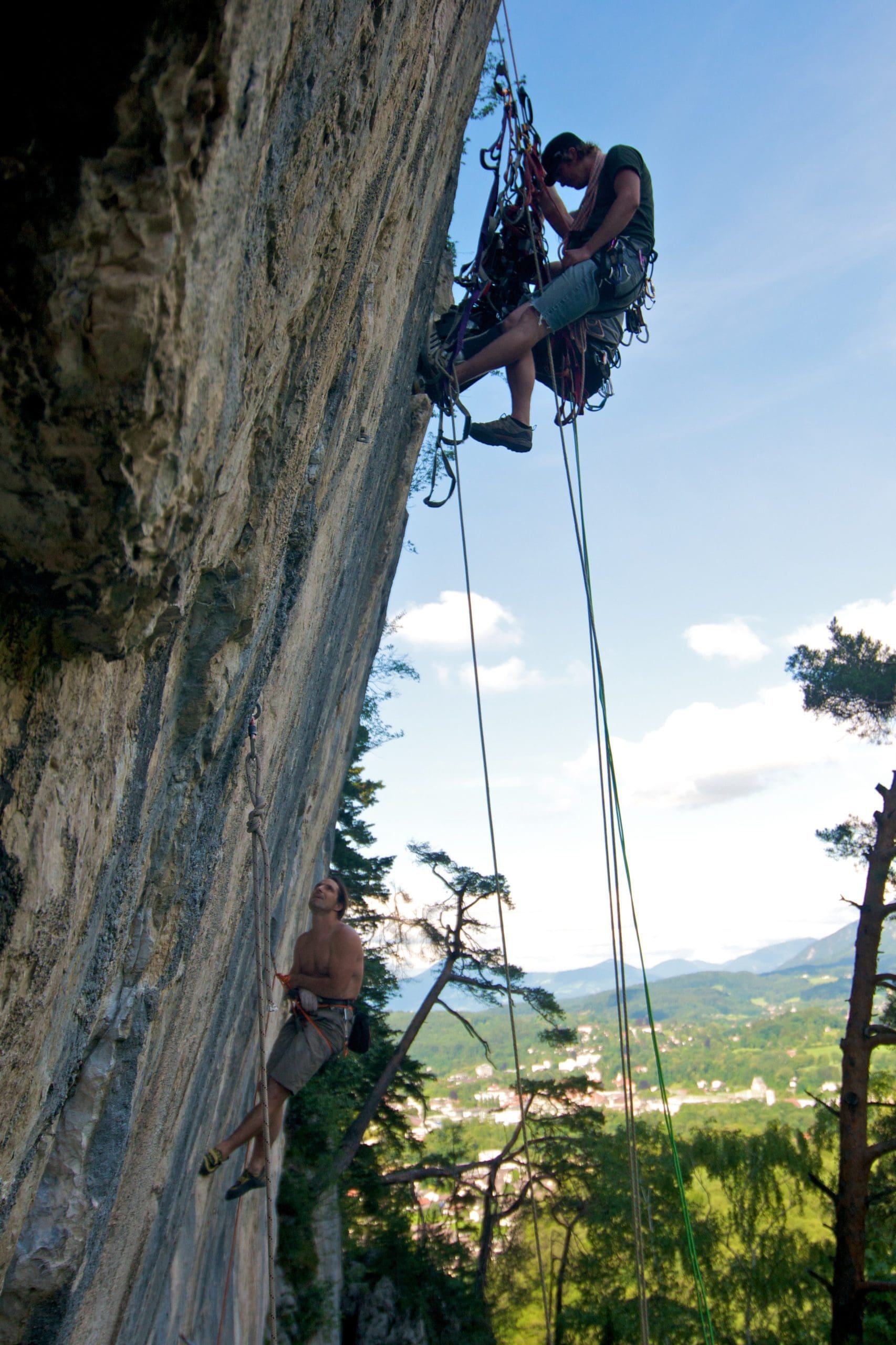 Two climbers on a rock face with ropes and equipment