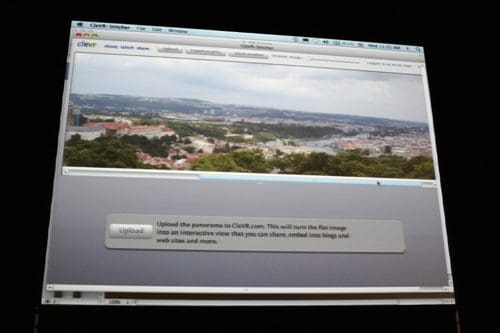 A computer screen displaying a panoramic view of a city. The interface shows an upload button to turn the flat image into an interactive format for sharing on blogs and websites.