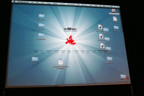 A computer screen displaying a desktop with a light blue background radiating light beams. Various folders are arranged on the screen, with one folder labeled 'on AIR tour' prominently featured.