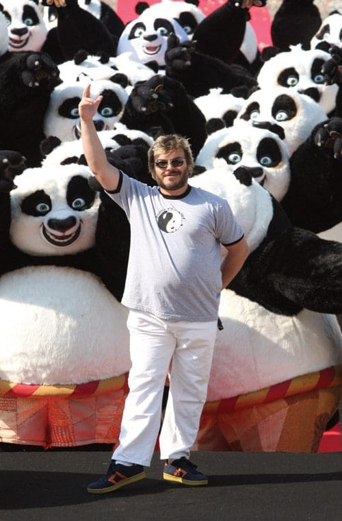A man with sunglasses and a gray t-shirt posing joyfully in front of a large group of panda mascots, all featuring black and white fur and playful expressions, on a festive backdrop.