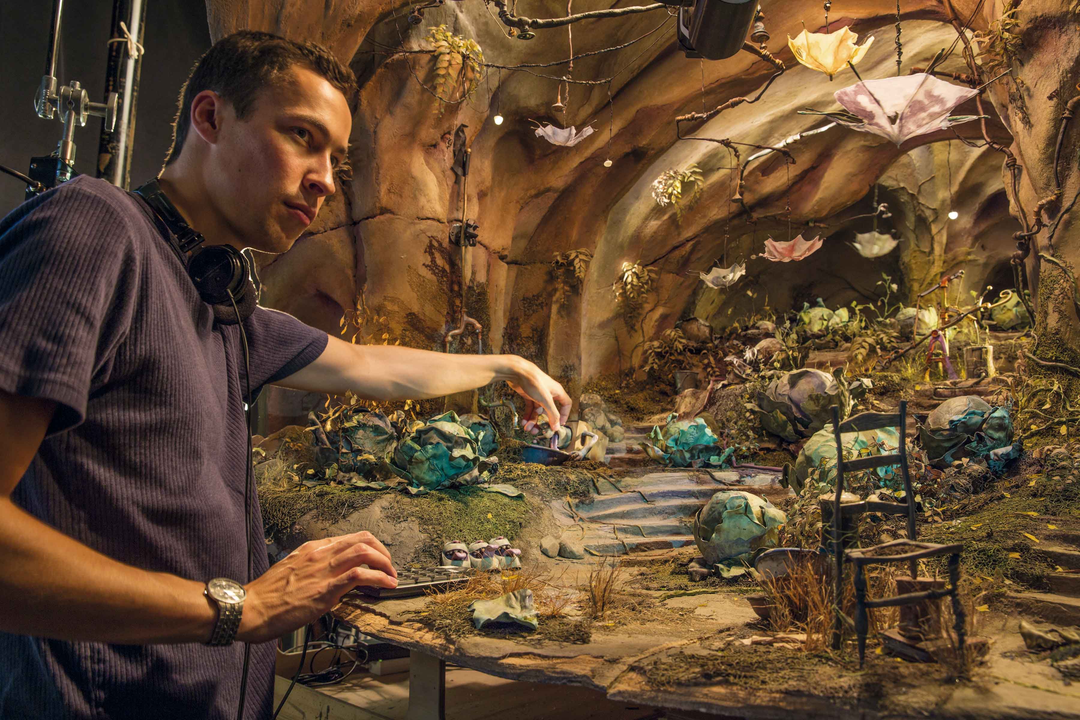 A person manipulating a miniature model in a creative studio setting.