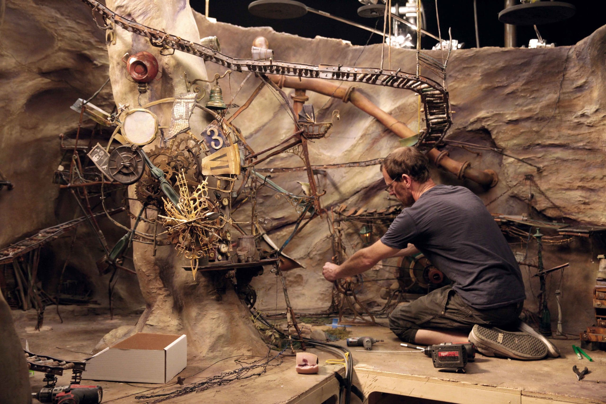 A person working on a mechanical set design in a workshop.