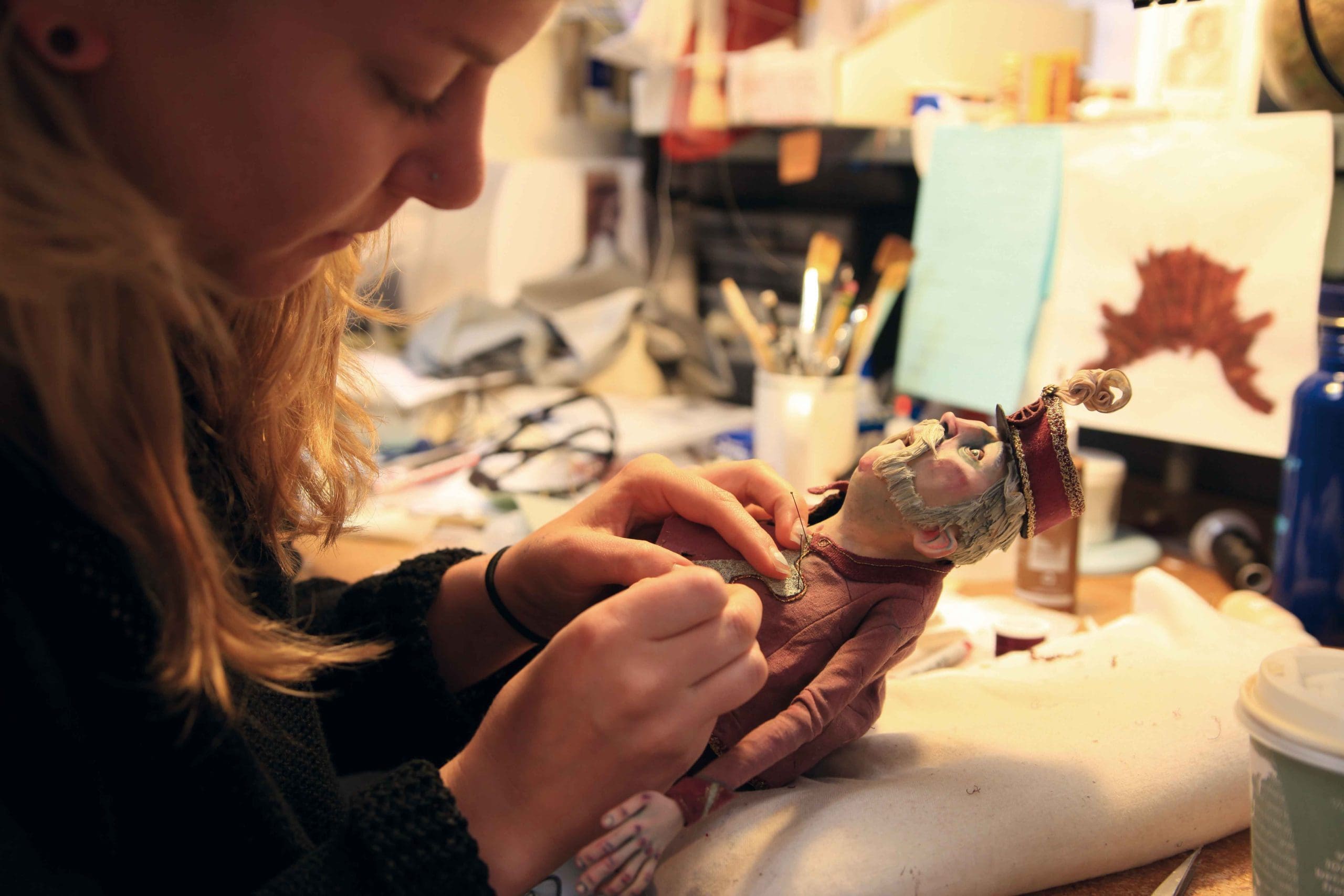A person working on a puppet in a workshop.