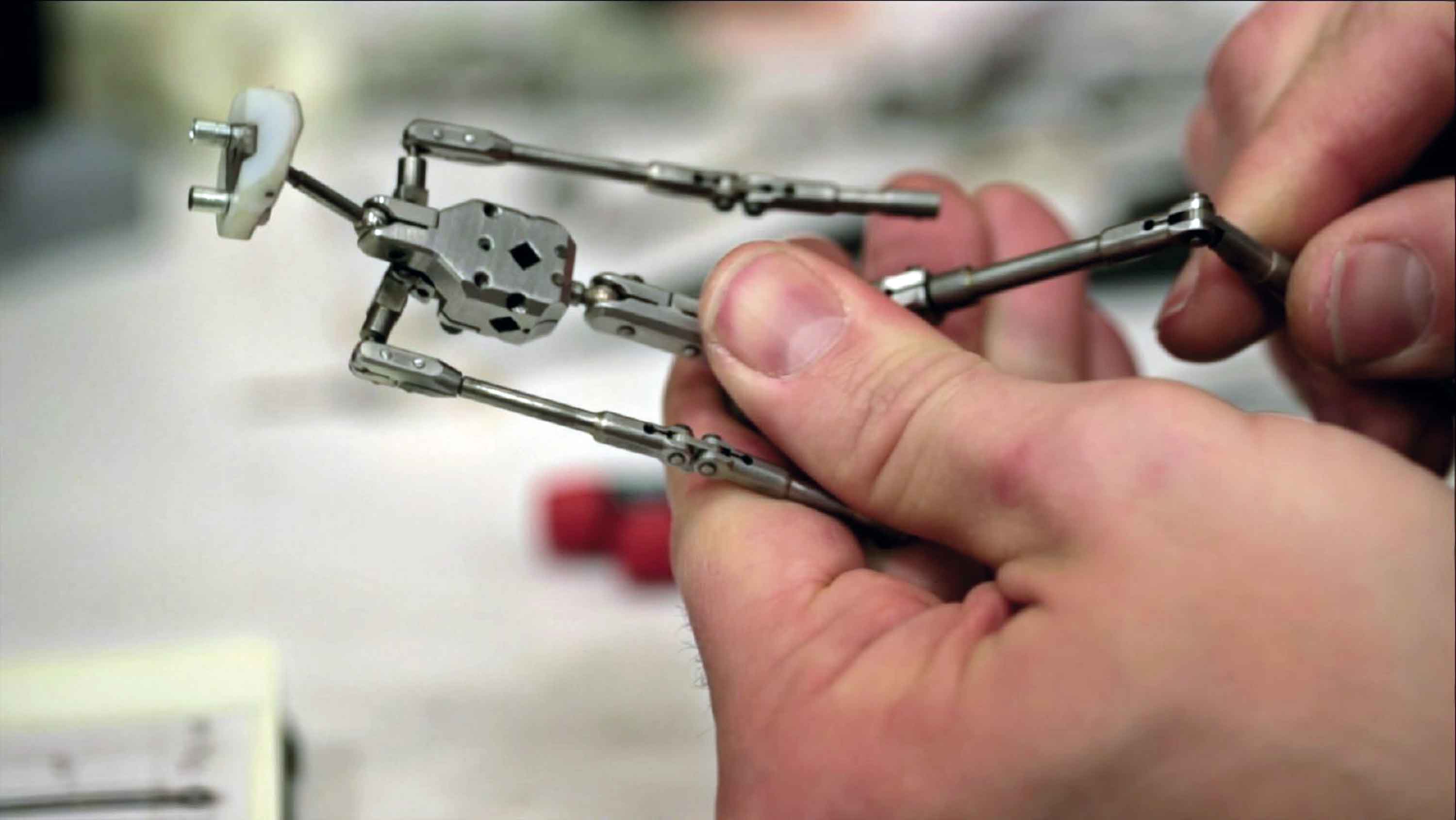 A person assembling a small articulated robot figure with metal joints.