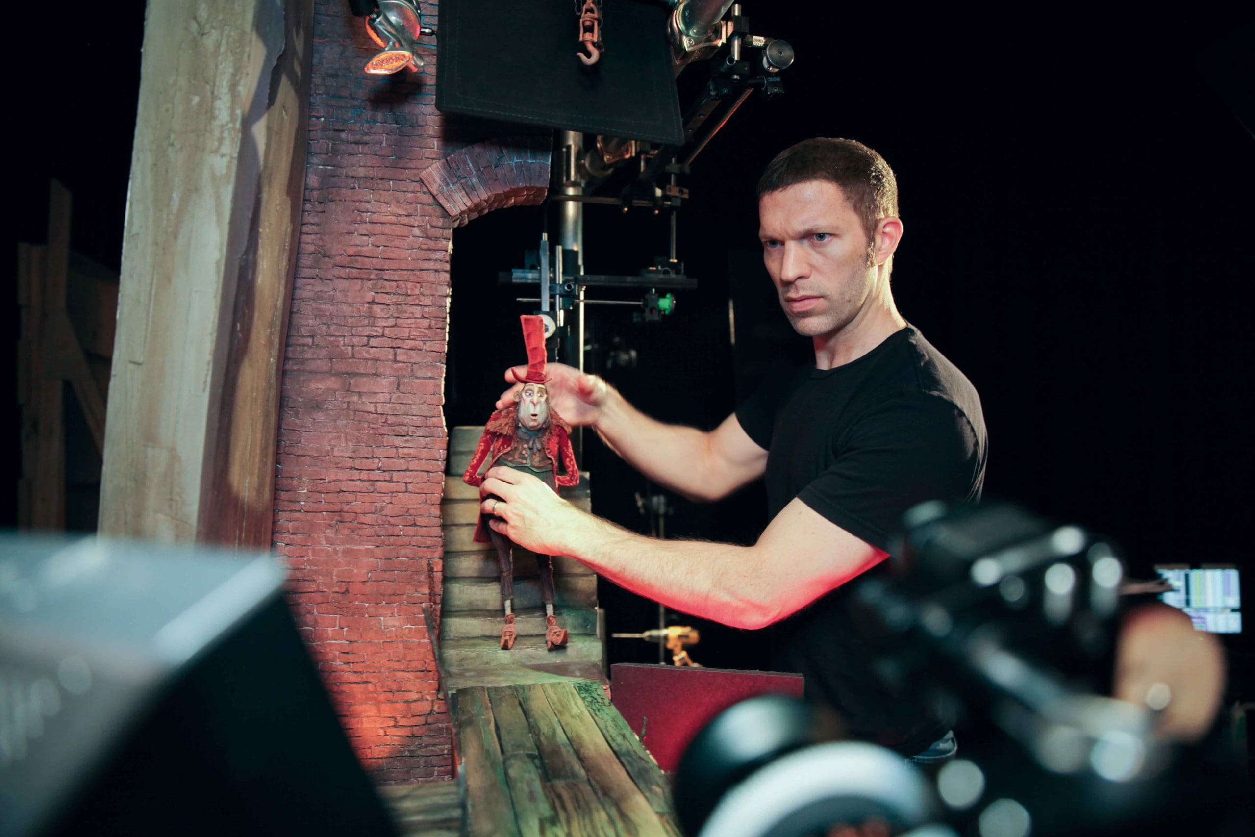 A man manipulating a puppet in a film studio setting.