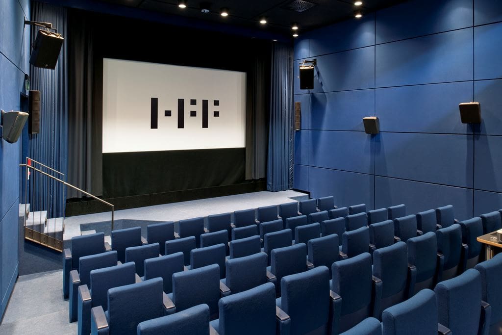 Empty cinema hall with blue seating and a projection screen