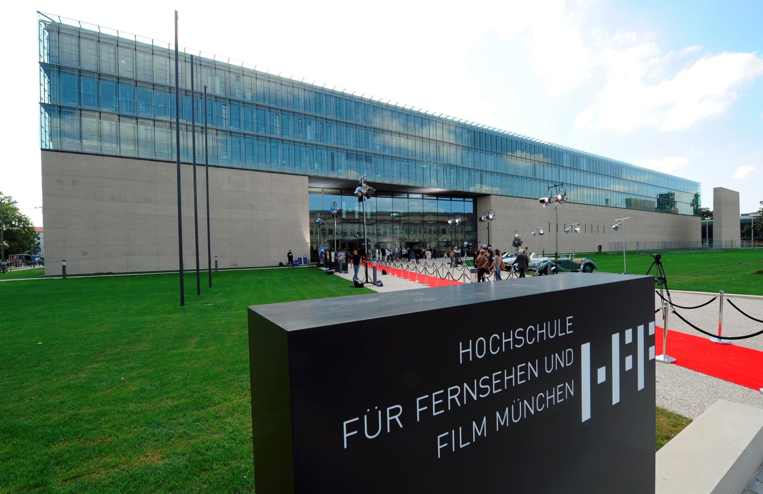 Exterior view of a modern film school building with a red carpet entrance.