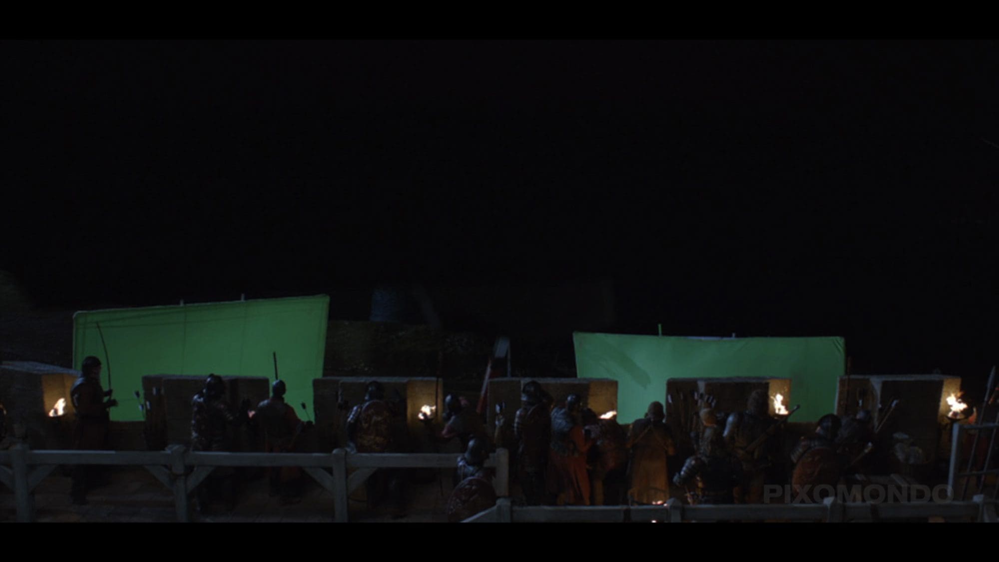 Actors in costumes on a film set with green screens at night.