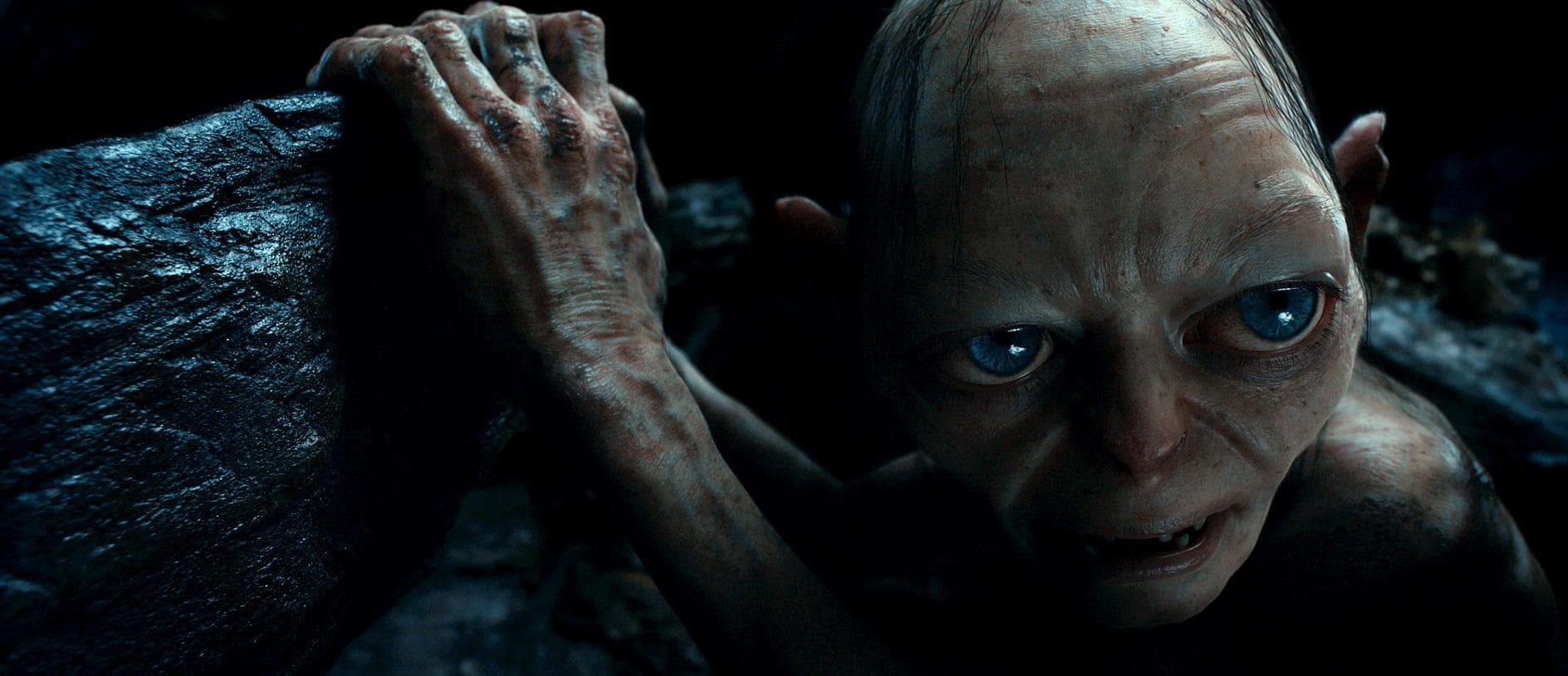 A creature with large eyes and pale skin clutching a rock in a dark environment.