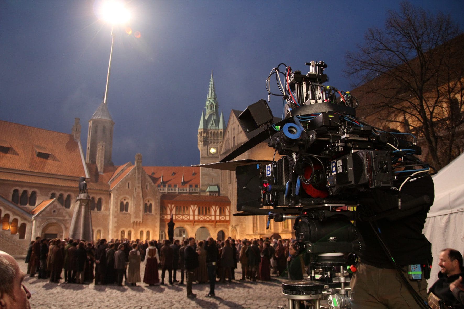 Film crew filming a night scene in a historic square.