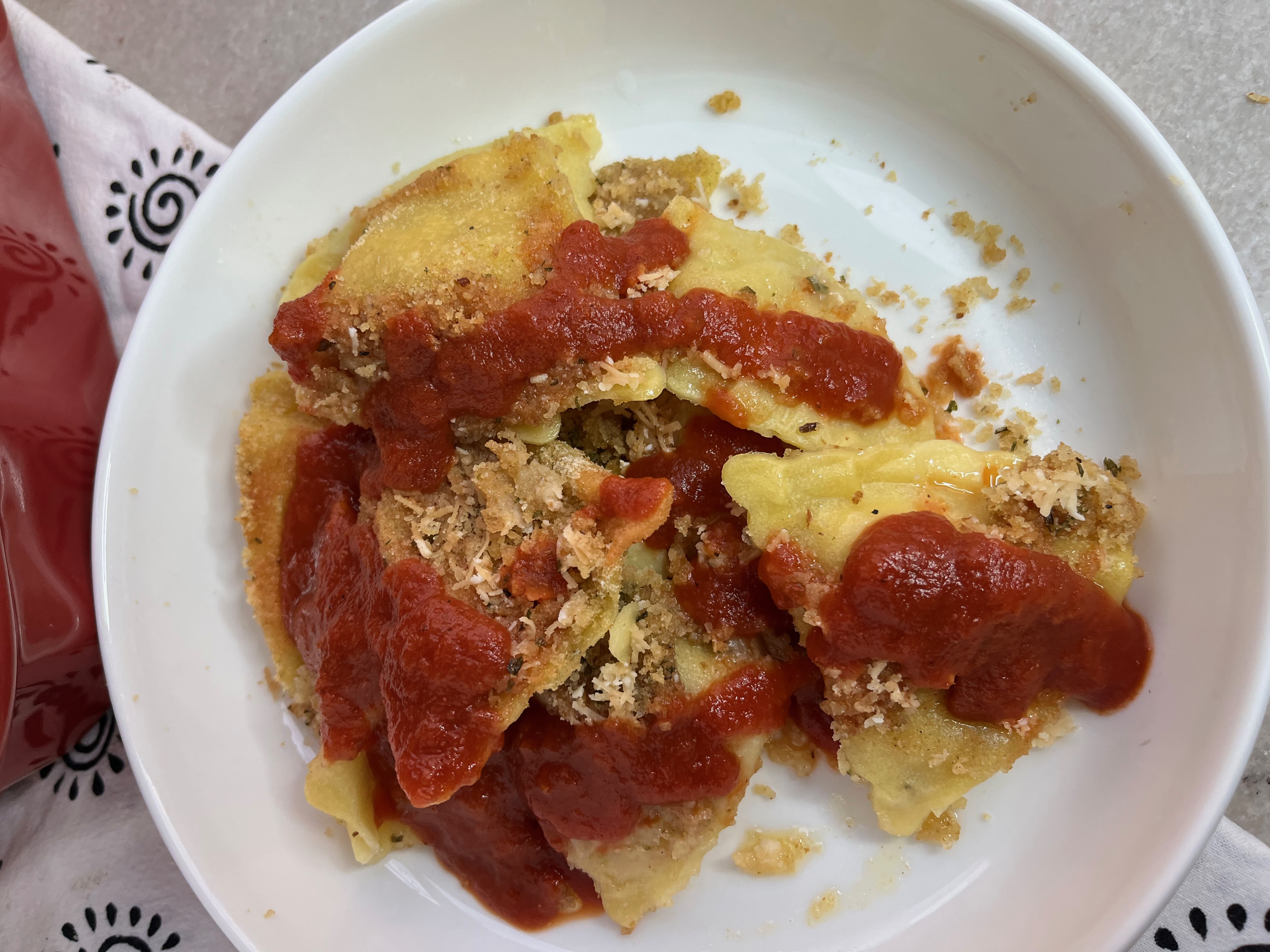 Cooked raviolis layered with mozzarella cheese and a bread crumb mixture with butter and parmesan cheese. Bake these layers until crispy and brown. Serve with warm marinara sauce poured on top.