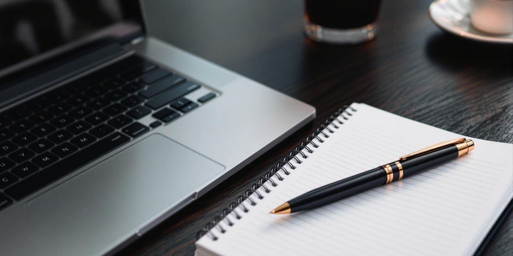 Escrita sofisticada com laptop e bloco de notas.
