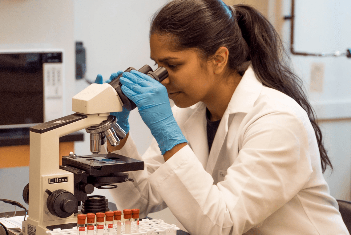 Lady looking at samples through a microscope