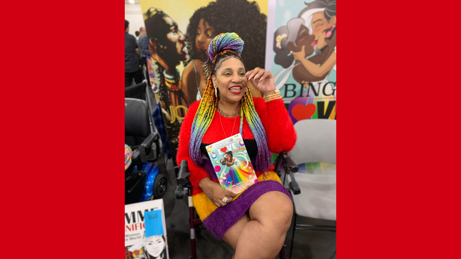 Graphic with a red background and a photo of Tee Franklin. Tee is attending a signing event for comic artists. She is sitting in a burgundy rollator walker, laughing as she holds a copy of her comic Bingo Love, on the cover is a drawing of two mature Black women embracing each other as they kiss, in skirts featuring the colours of the Pride flag. Tee is wearing a multicolored dress in a soft fuzzy texture. The colors are red, black, yellow, and purple. Tee’s hair is styled in traditional extension braids in colours to match her dress.