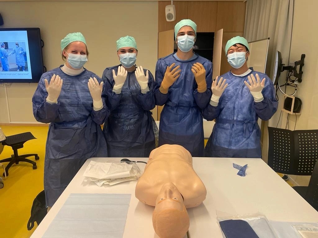 The Precision Medicine lab students dressed in medical attire and practicing the steps of gowning, gloving, and preparing for surgery.
