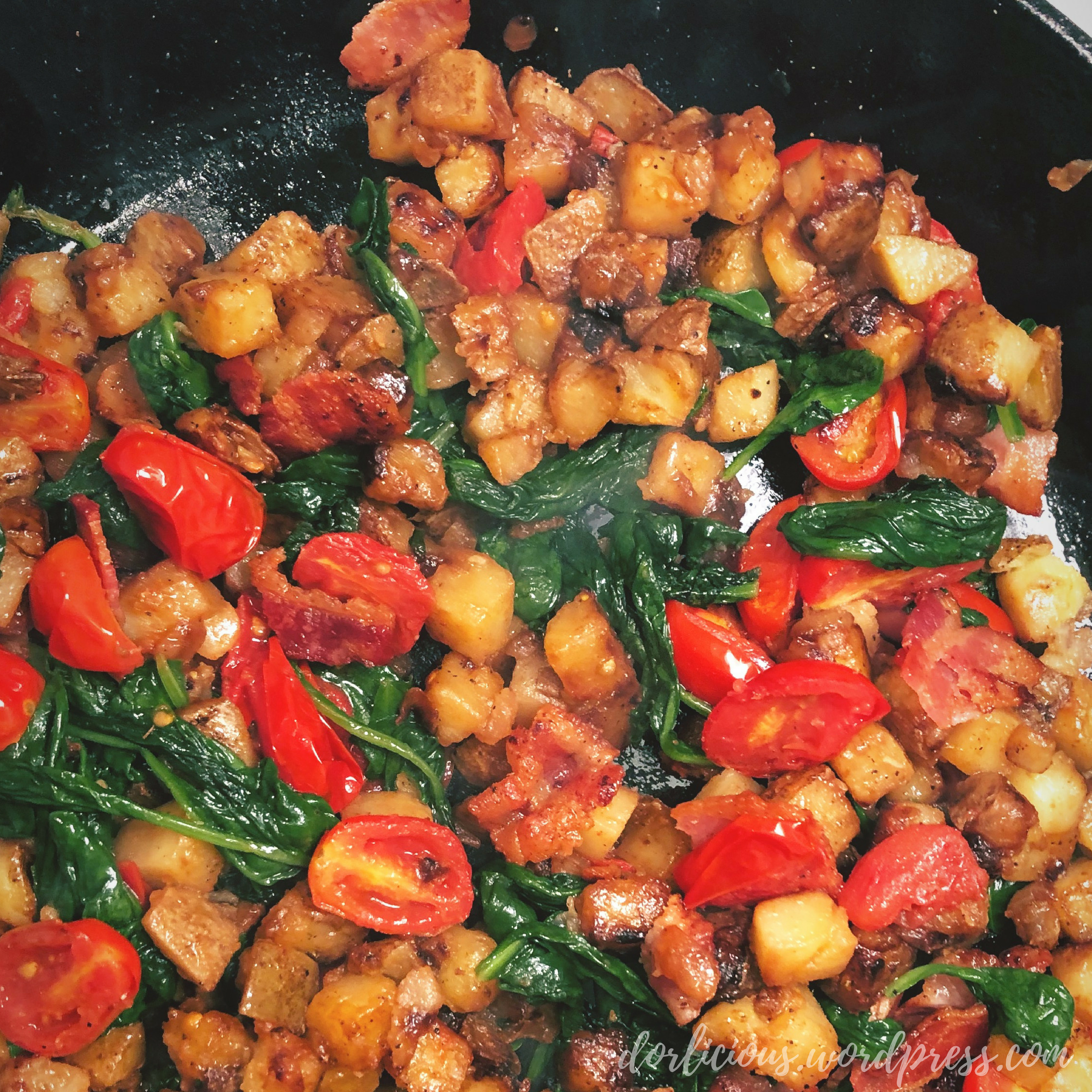 Bacon, tomato, spinach, potato and onion in a case iron skillet