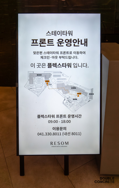 스테이타워의 프론트 운영 안내가 적힌 흰색 안내판으로, 체크인과 아웃 시 이동 경로가 표시되어 있다.